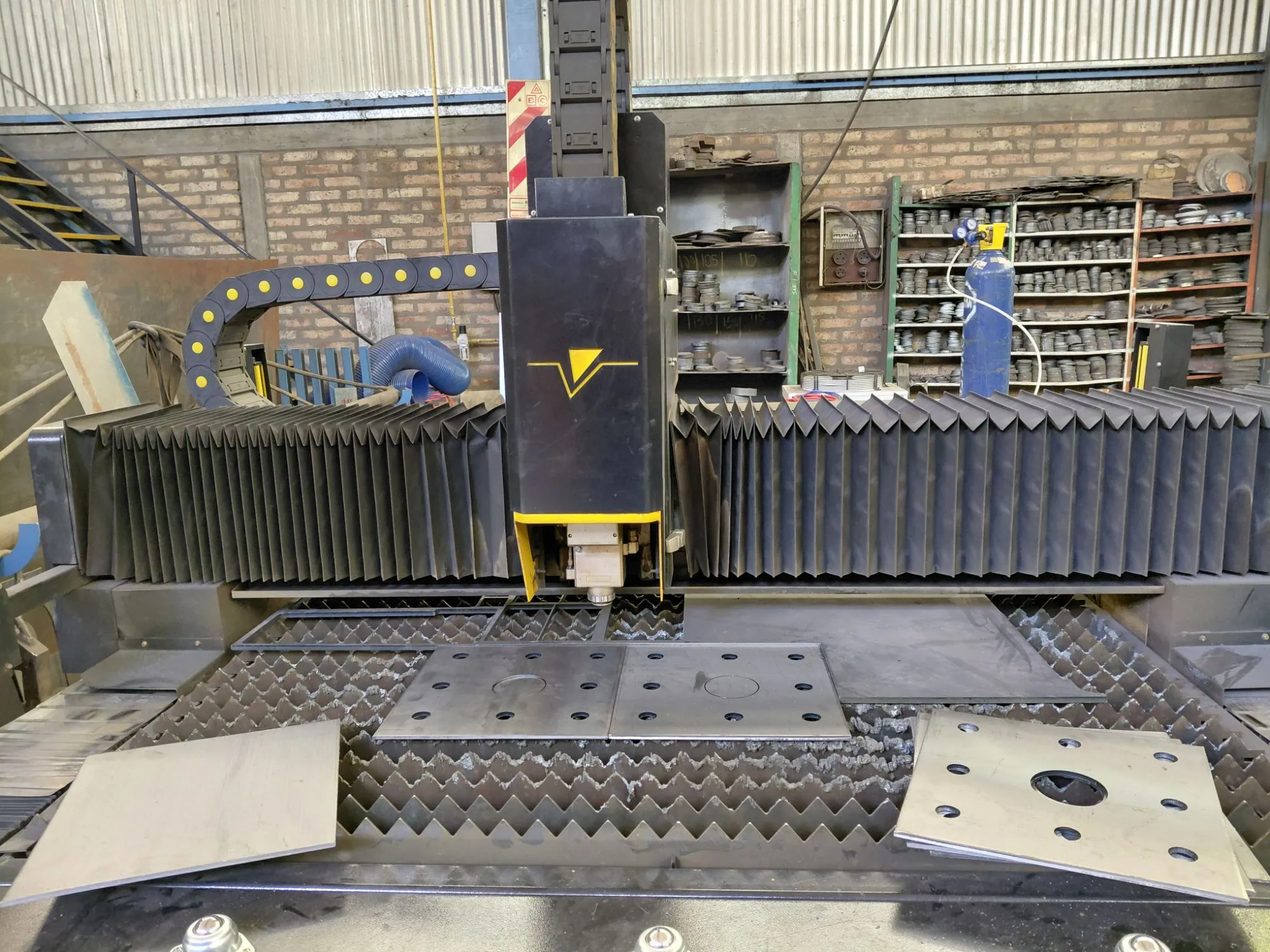 Máquina de corte láser Patagonia CNC en el taller de MAESPEC, con placas recién cortadas sobre la mesa